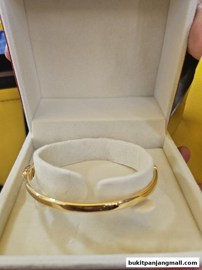 A gold bracelet with small stones displayed in a velvet-lined jewelry box.