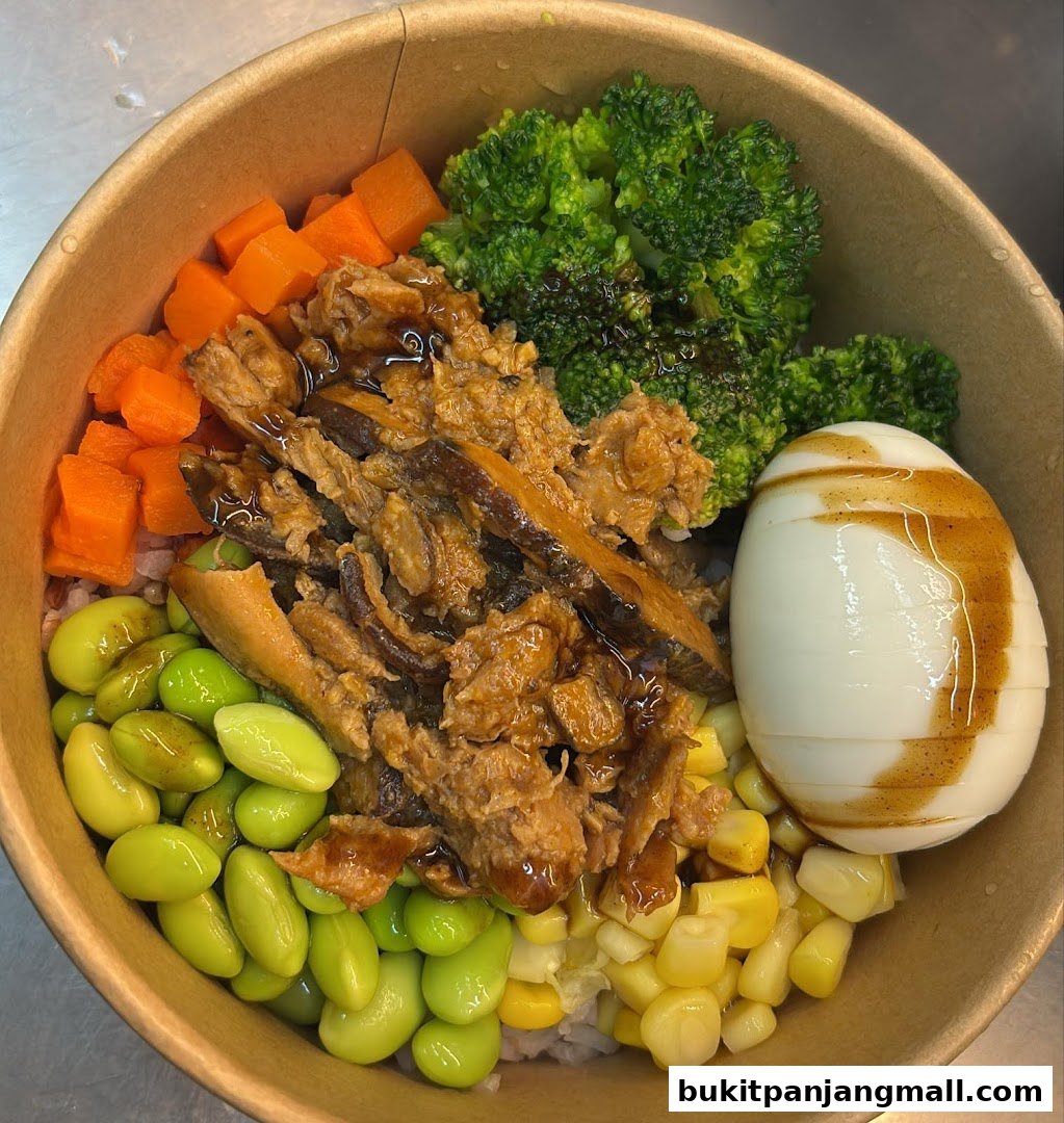 A healthy and colorful bowl of rice with edamame, corn, carrots, broccoli, shredded meat, and a boiled egg.
