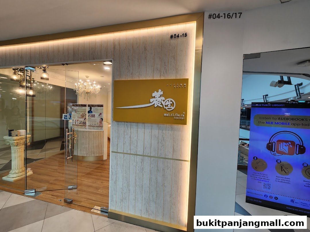 The entrance of Multiflora TCM Spa, featuring a modern design with glass doors and a prominent yellow sign.