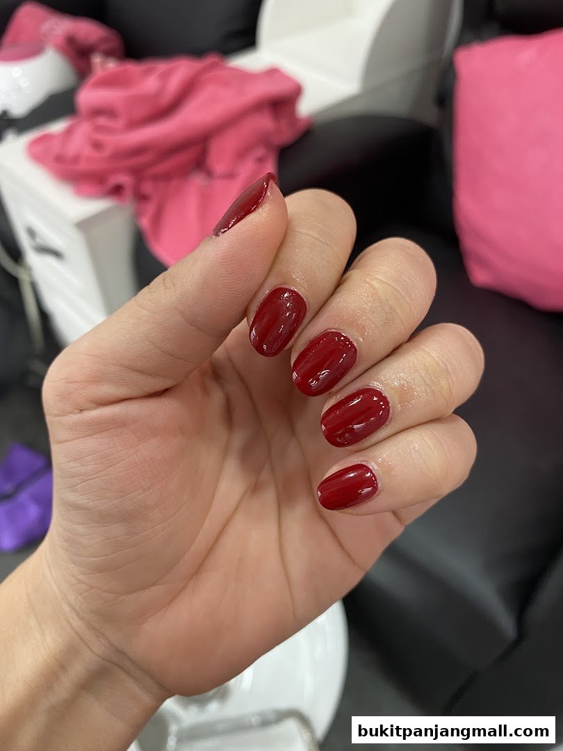A close-up of a hand with perfectly manicured, glossy dark red nails.