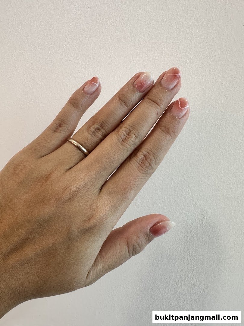 A hand with beautifully manicured nails featuring a subtle gradient and delicate white line art.