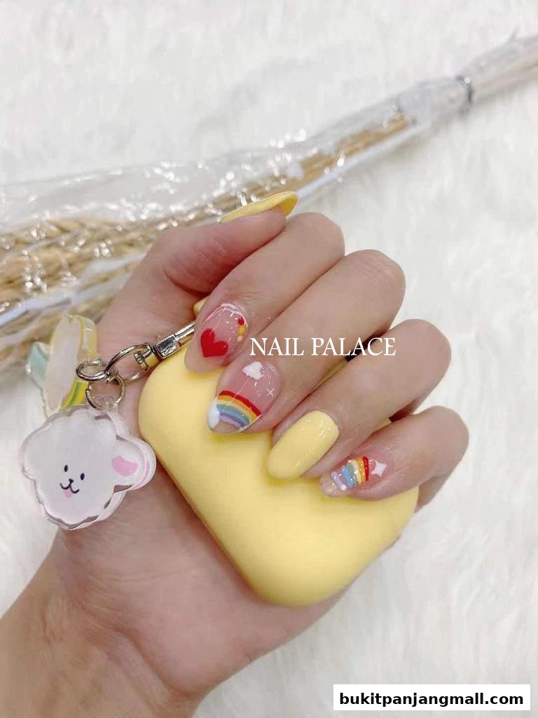 A hand with colorful rainbow and heart-themed nails, holding a yellow object and a cloud charm.