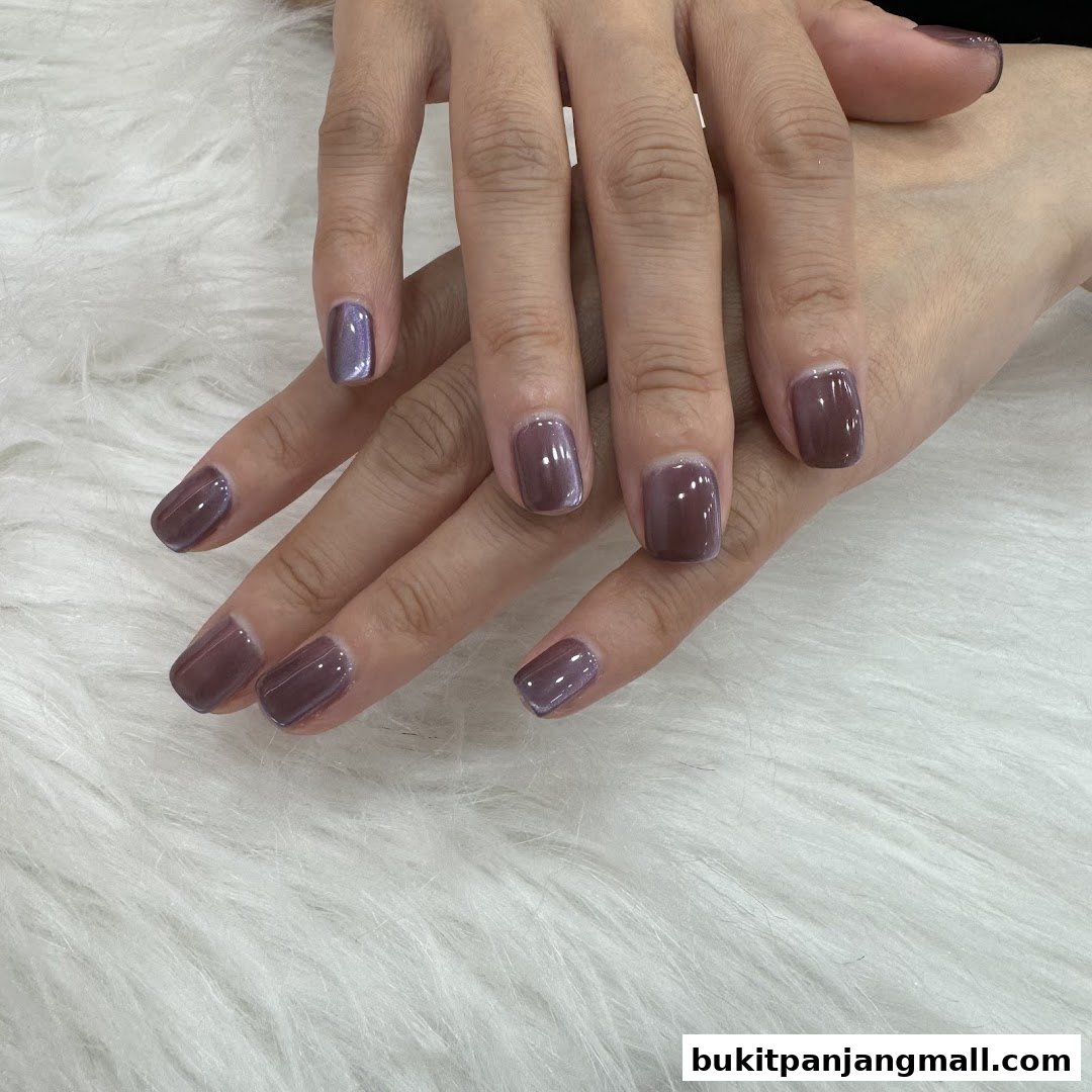 A close-up shot of a person's hands with beautifully manicured nails in a muted purple shade.