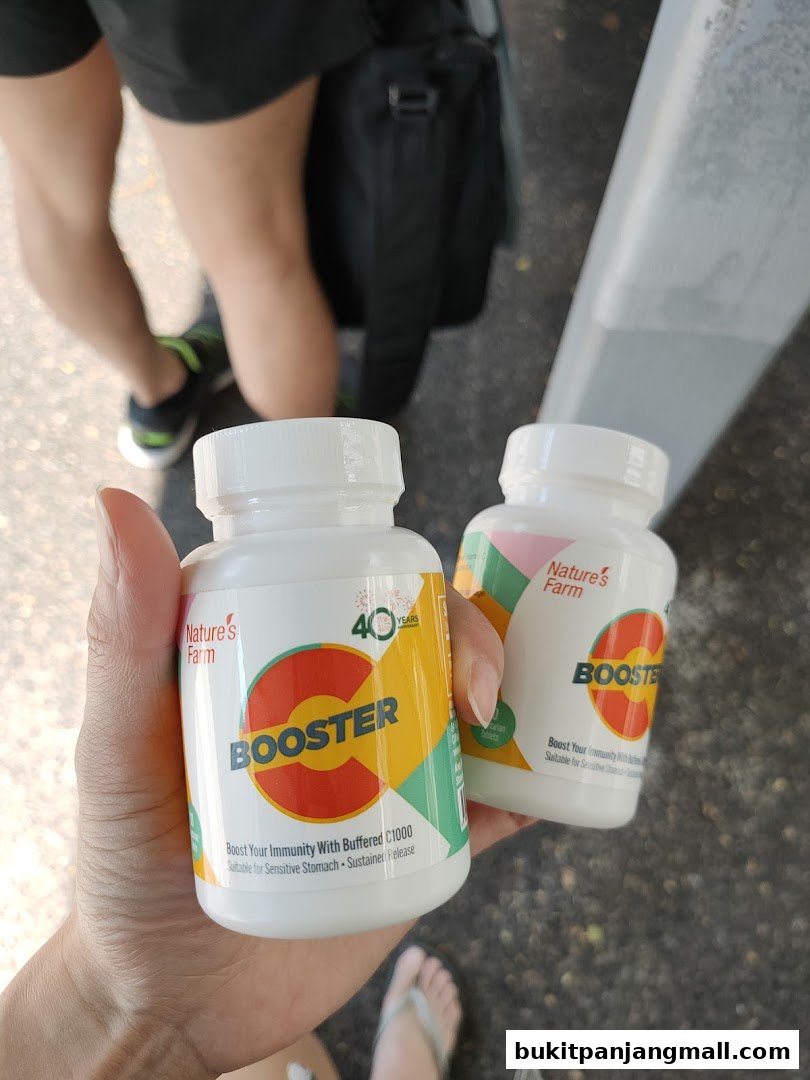 Hands holding two bottles of Nature's Farm Booster supplements.