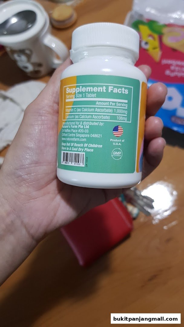 A hand holds a bottle of Nature's Farm Vitamin C supplement with supplement facts visible.