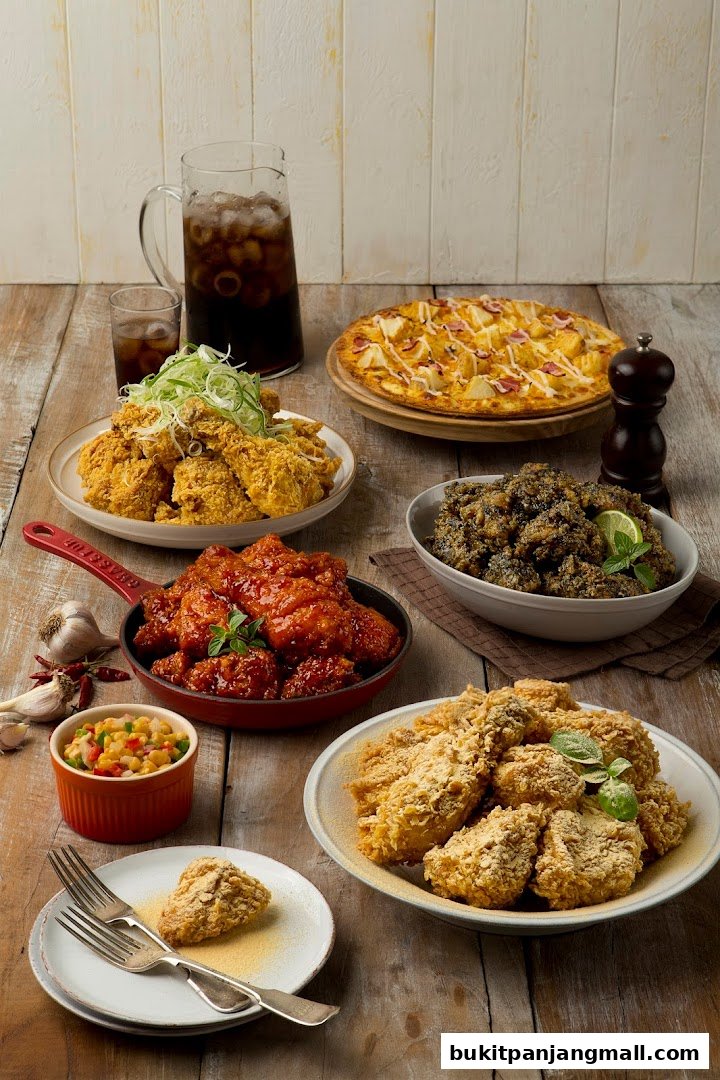 A spread of delicious fried chicken, pizza, and drinks on a wooden table.