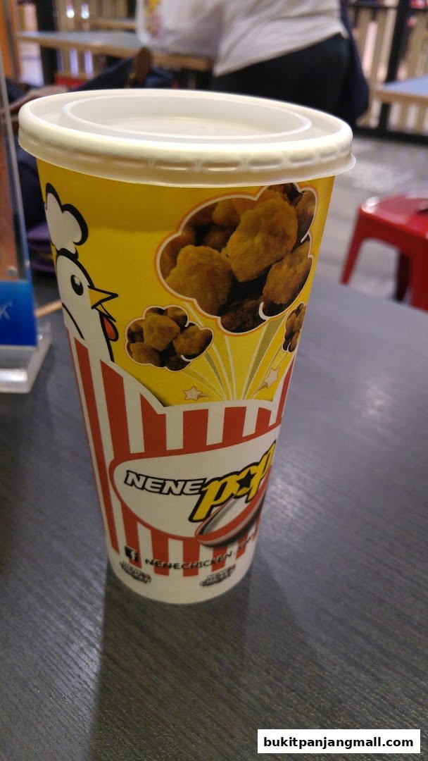 A close-up of a NeNe Chicken popcorn chicken cup with a cartoon chicken and images of chicken.