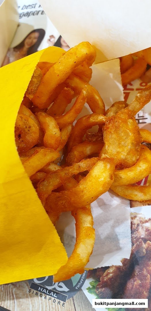 A close-up shot of crispy, seasoned curly fries spilling out of a yellow paper bag.