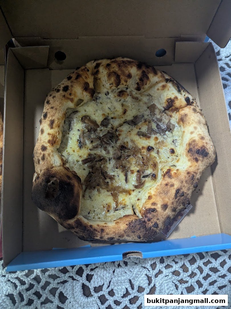A delicious-looking pizza with a golden crust and creamy white sauce topped with caramelized onions.