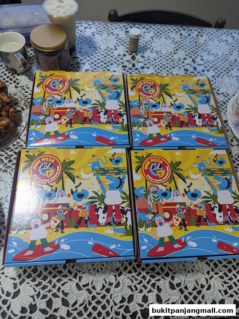 Four pizza boxes with colorful, cartoonish designs are laid out on a table.