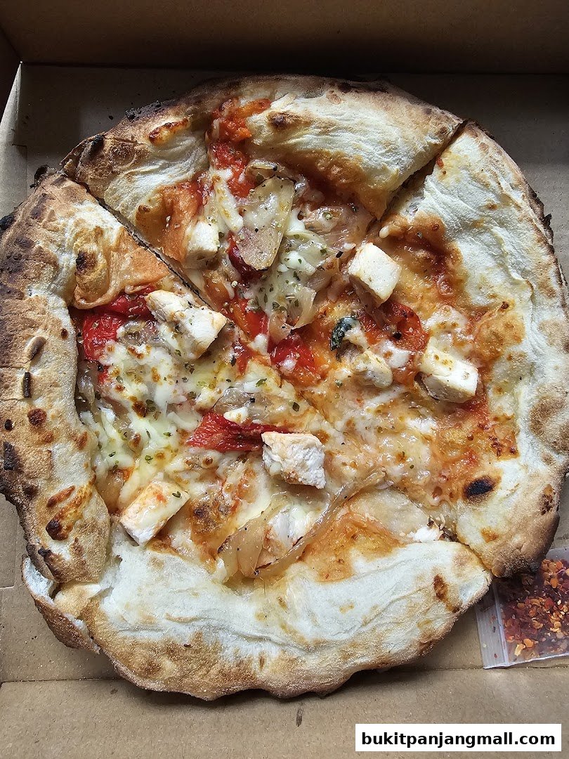 A delicious pizza with chicken, cheese, and red peppers in a pizza box.