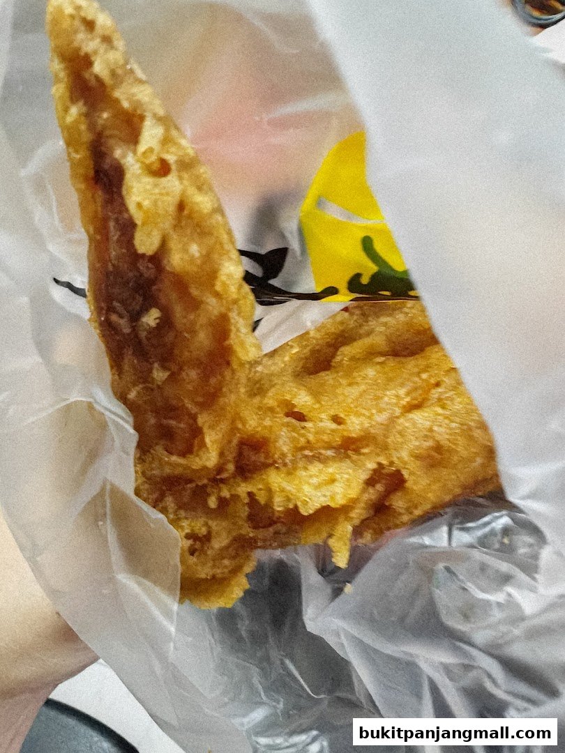 A close-up shot of a crispy fried chicken wing in a plastic bag.