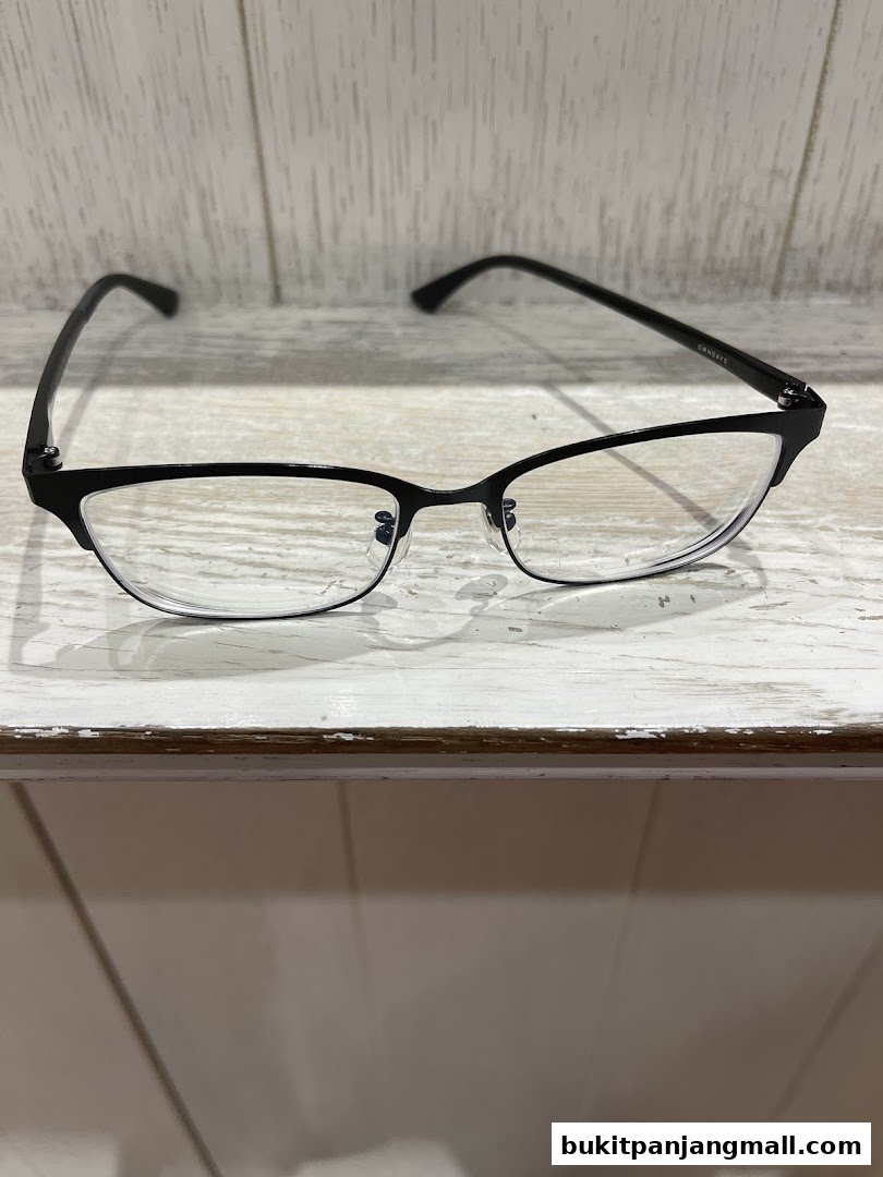 A pair of black-rimmed eyeglasses with clear lenses rests on a white wooden surface.