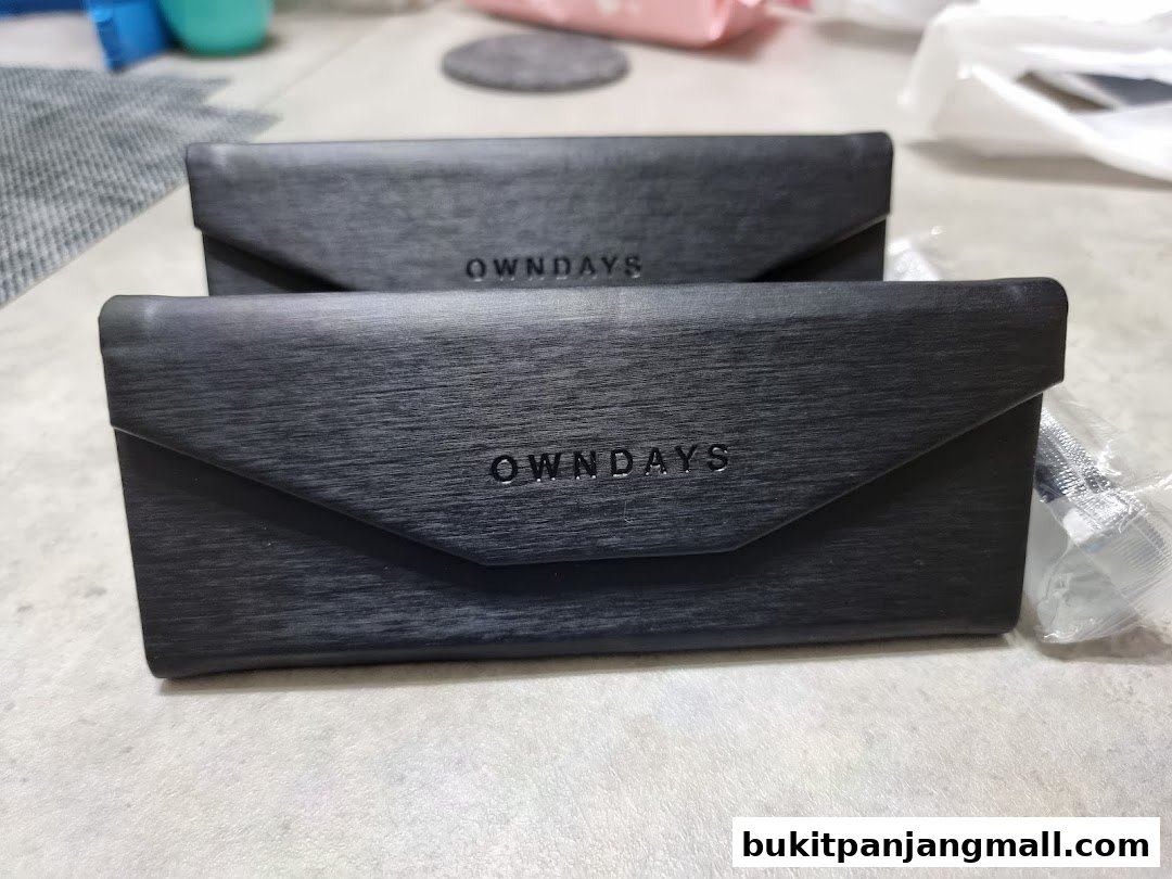 Two black OWNDAYS branded glasses cases are displayed on a textured surface.