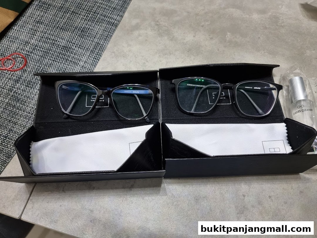 Two pairs of stylish eyeglasses in black cases with cleaning cloths and a bottle of glasses cleaner.
