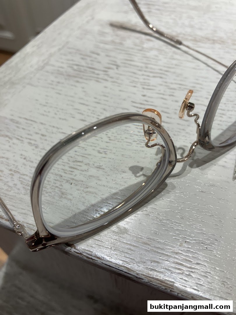 Close-up of stylish eyeglasses with silver frames and clear lenses on a textured surface.