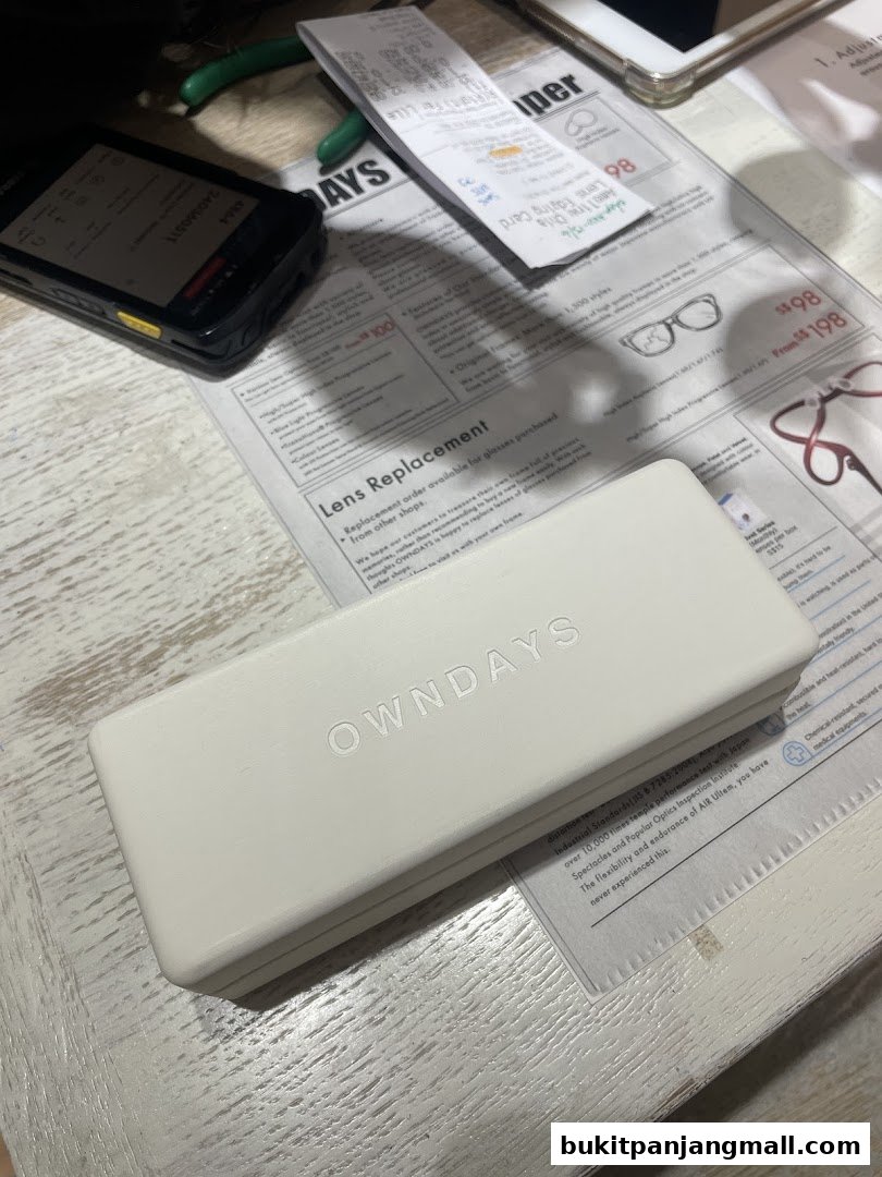 An OWNDAYS glasses case and promotional materials are laid out on a table.