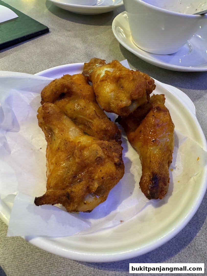 A plate of crispy, golden-brown chicken wings served on white paper.