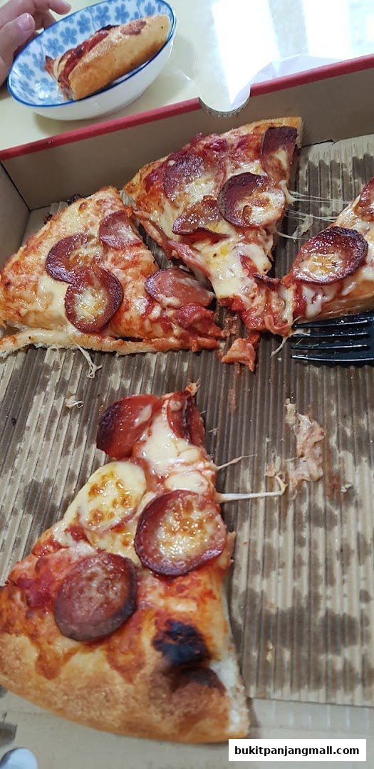 Slices of pepperoni pizza with melted cheese and a hot dog in a bowl.
