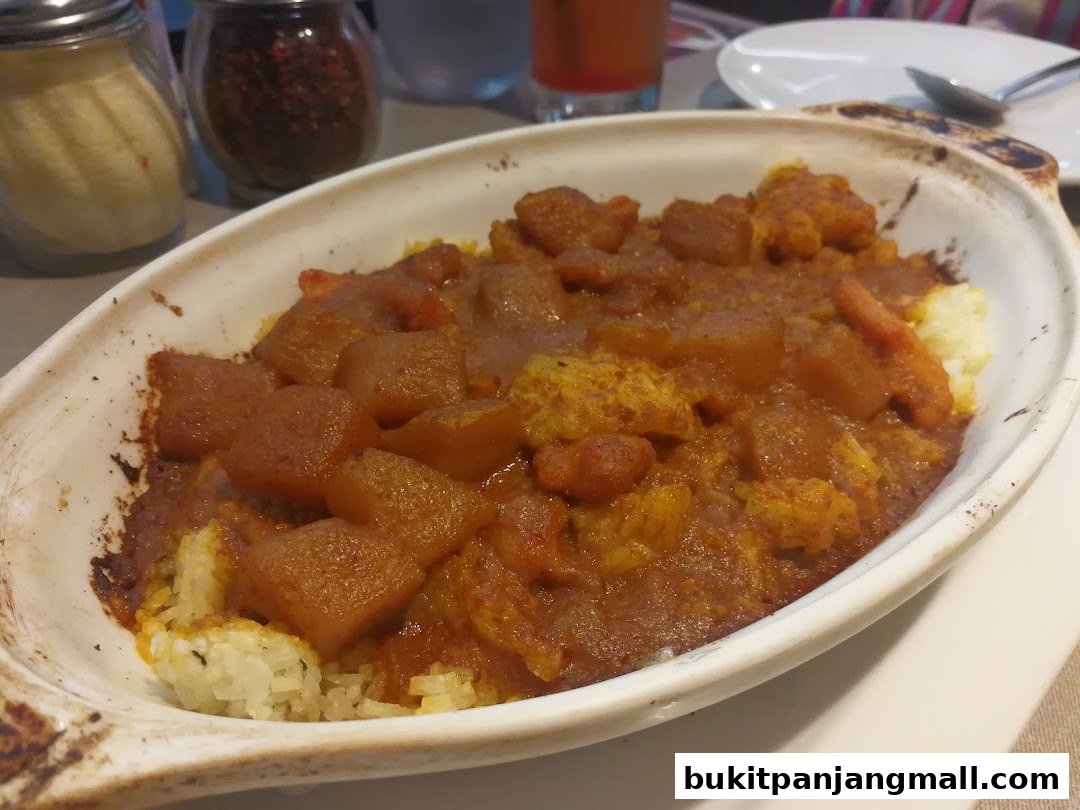 A close-up of a baked dish with rice and a hearty stew, served in a white oval baking dish.
