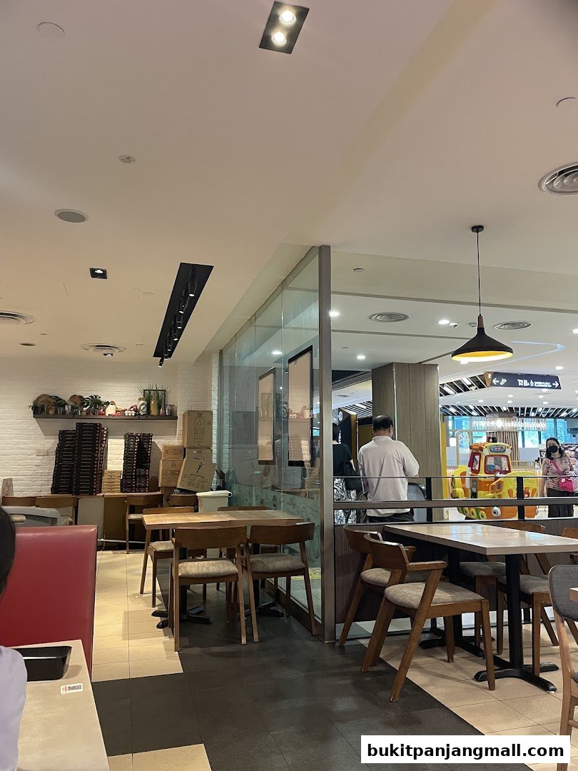 Interior view of a Pizza Hut restaurant with tables, chairs, and a glimpse of the mall beyond.