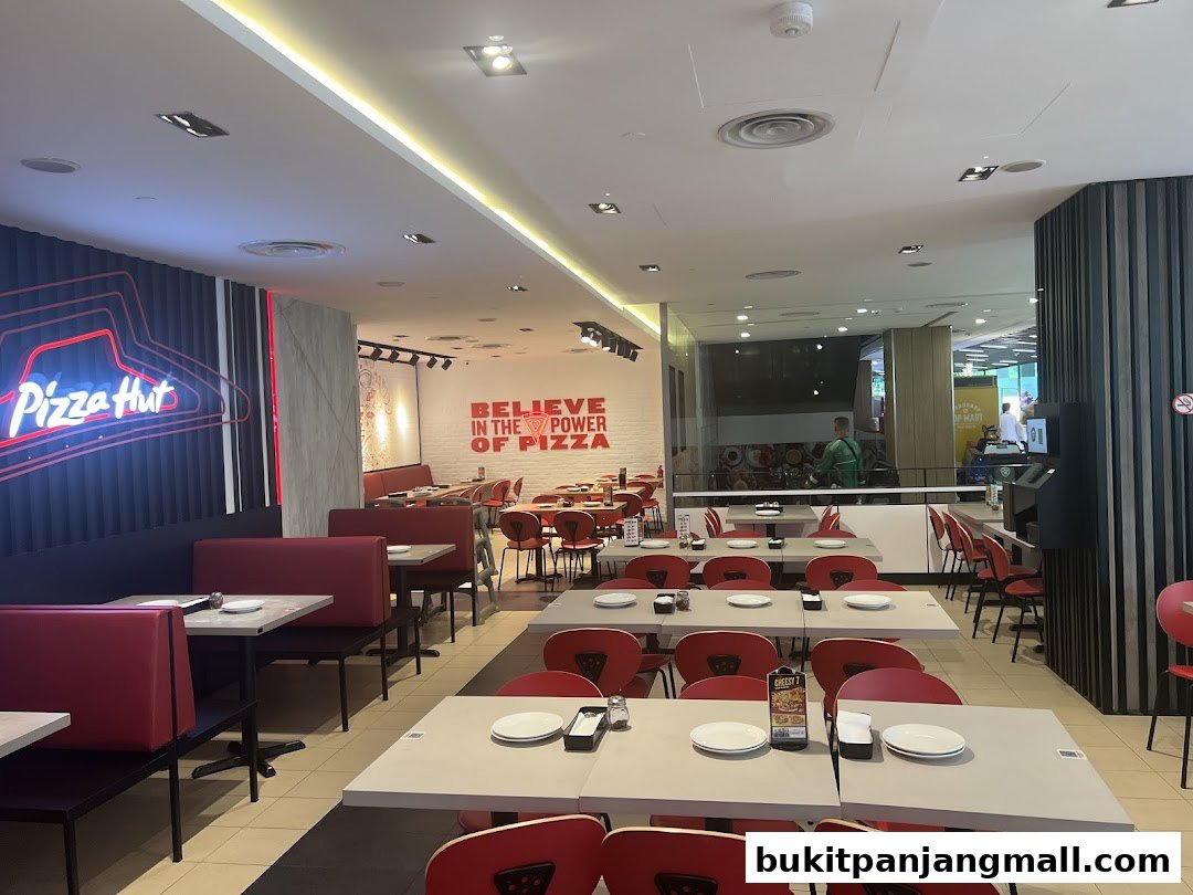 Interior view of a Pizza Hut restaurant with tables, chairs, and neon signage.