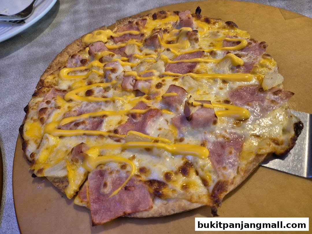 A close-up shot of a delicious pizza with ham, pineapple, and cheese, drizzled with cheese sauce.