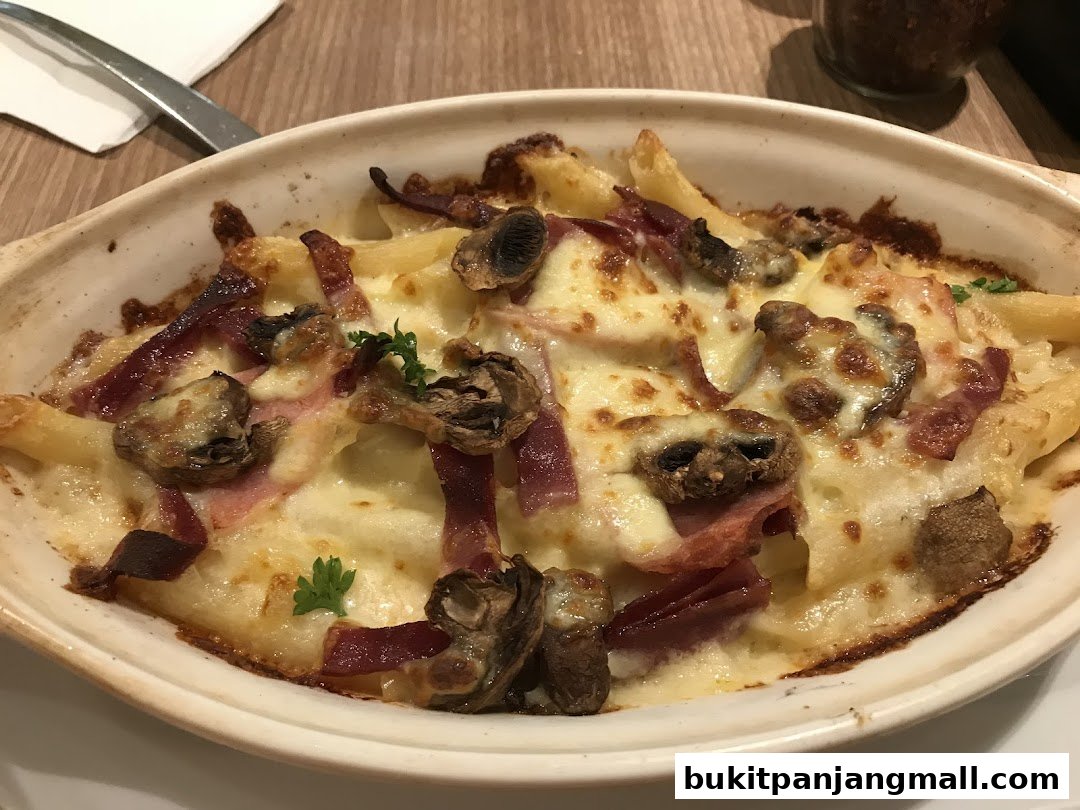 A close-up of a baked pasta dish with cheese, mushrooms, and ham.