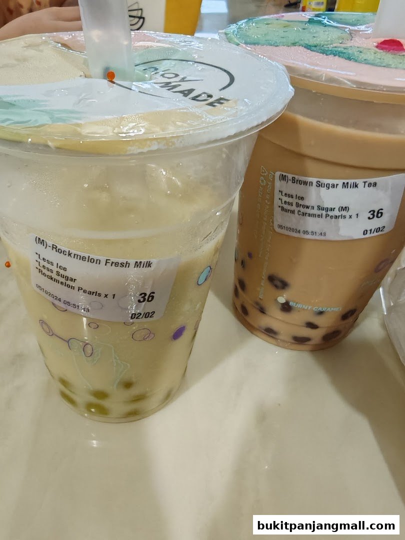 Two bubble tea drinks, one Rockmelon Fresh Milk and one Brown Sugar Milk Tea, are displayed on a table.