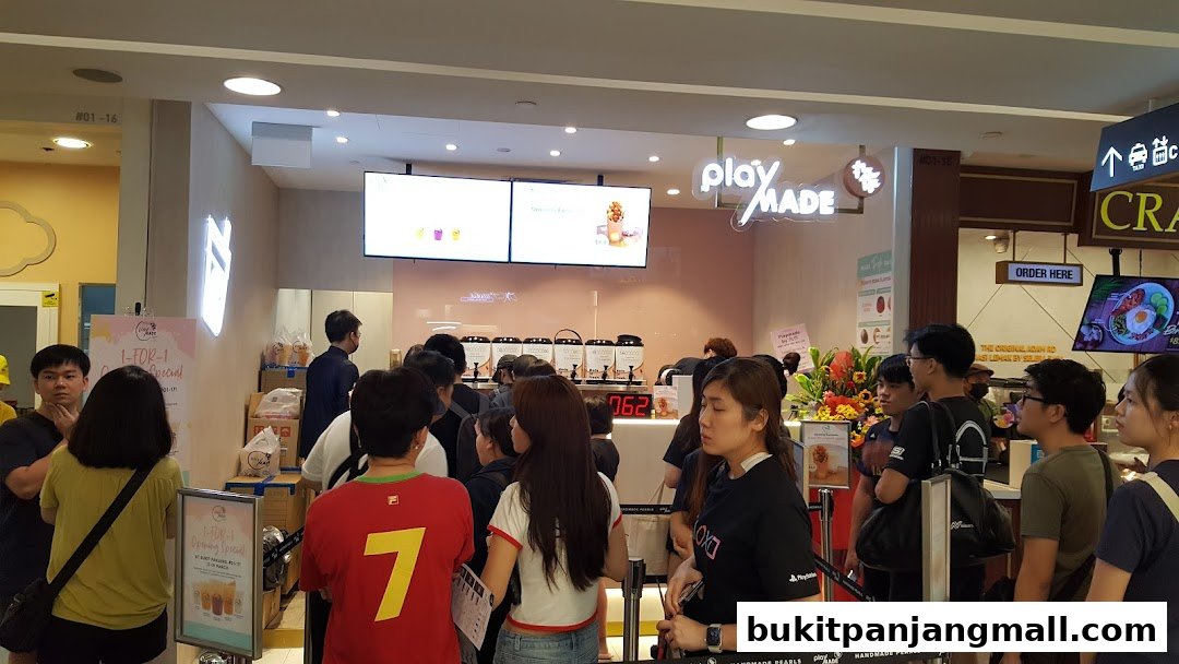 A busy PlayMade shop with customers queuing and a promotional sign for a 1-for-1 special.
