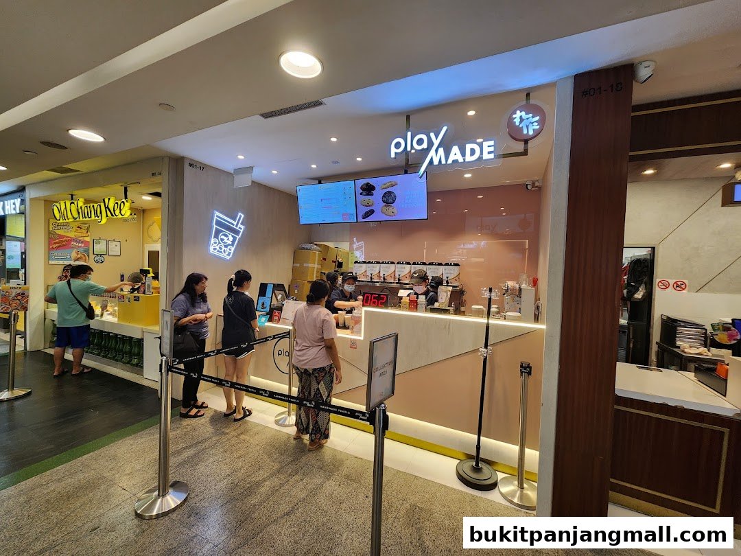 Customers queue at the PlayMade dessert shop, with a menu displayed on a screen.