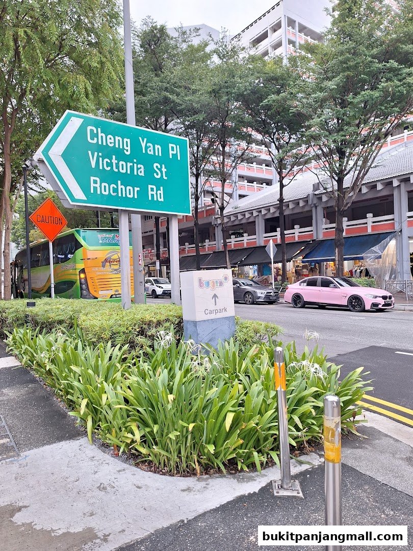 Street view with directional signs, a bus, cars, and shops in the background.