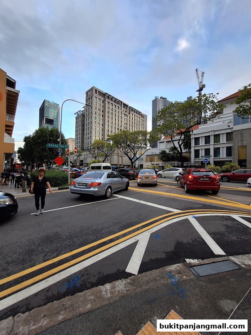 A street scene with cars, buildings, and a pedestrian on a cloudy day.