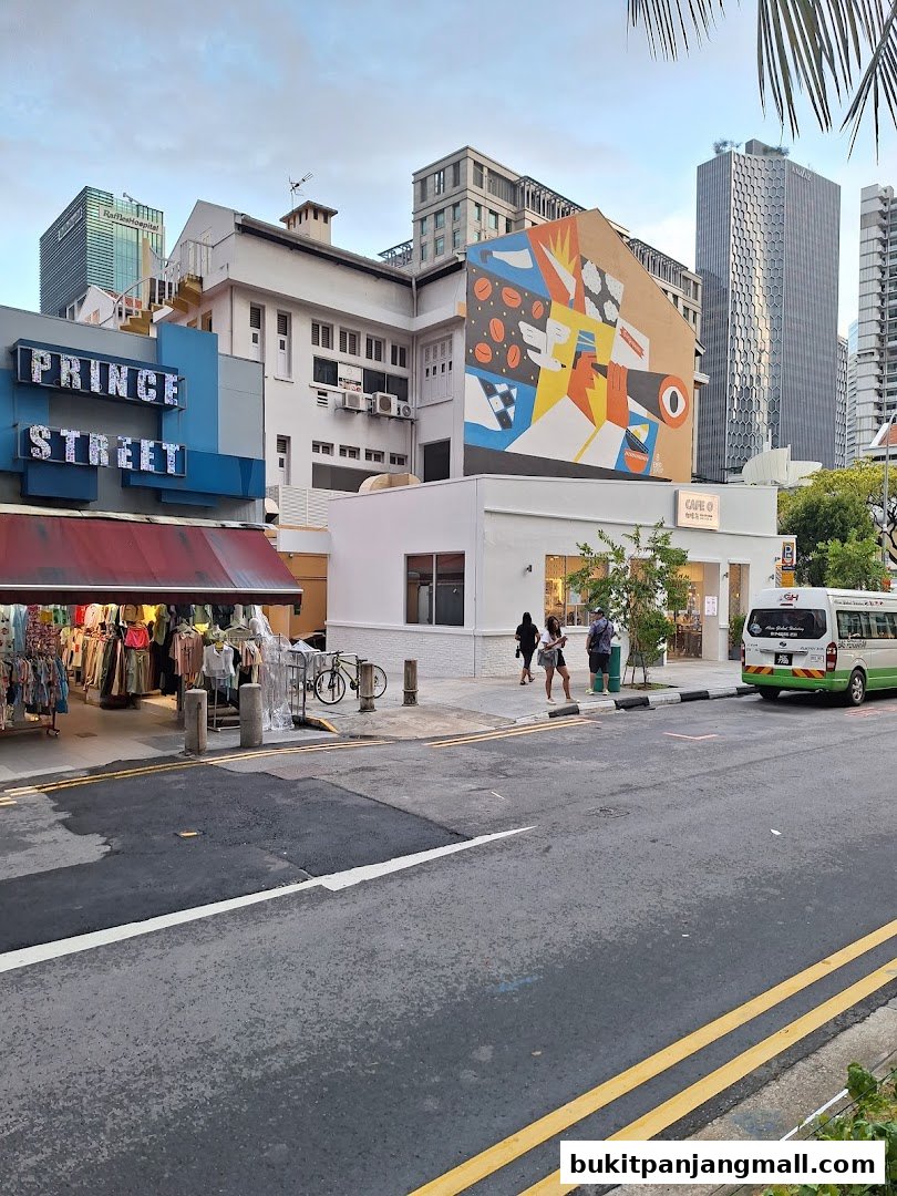 A street view of shops, including a clothing store and a cafe, with a mural on the building.