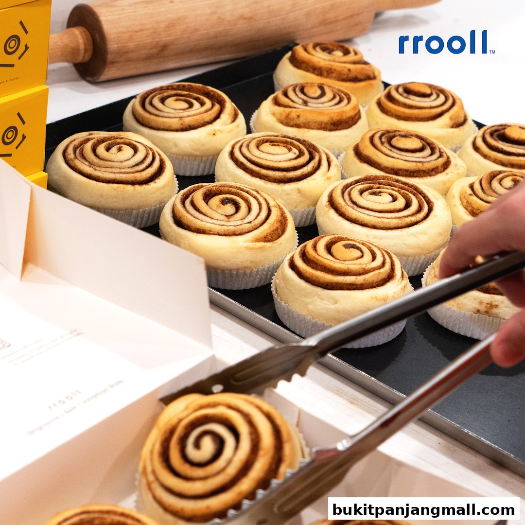 A tray of freshly baked cinnamon rolls is being served with tongs.