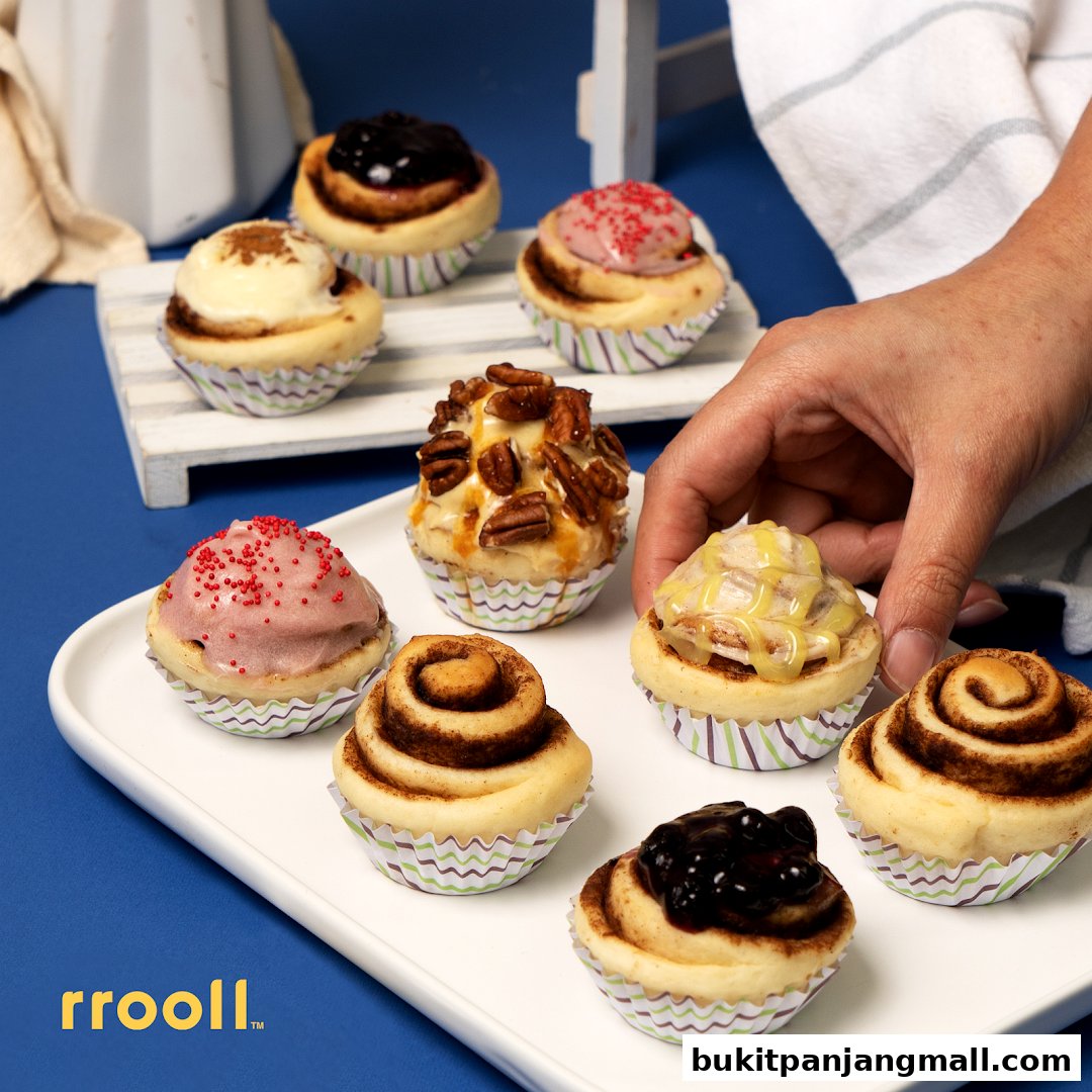 A hand reaching for a variety of delicious cinnamon rolls on a white platter.