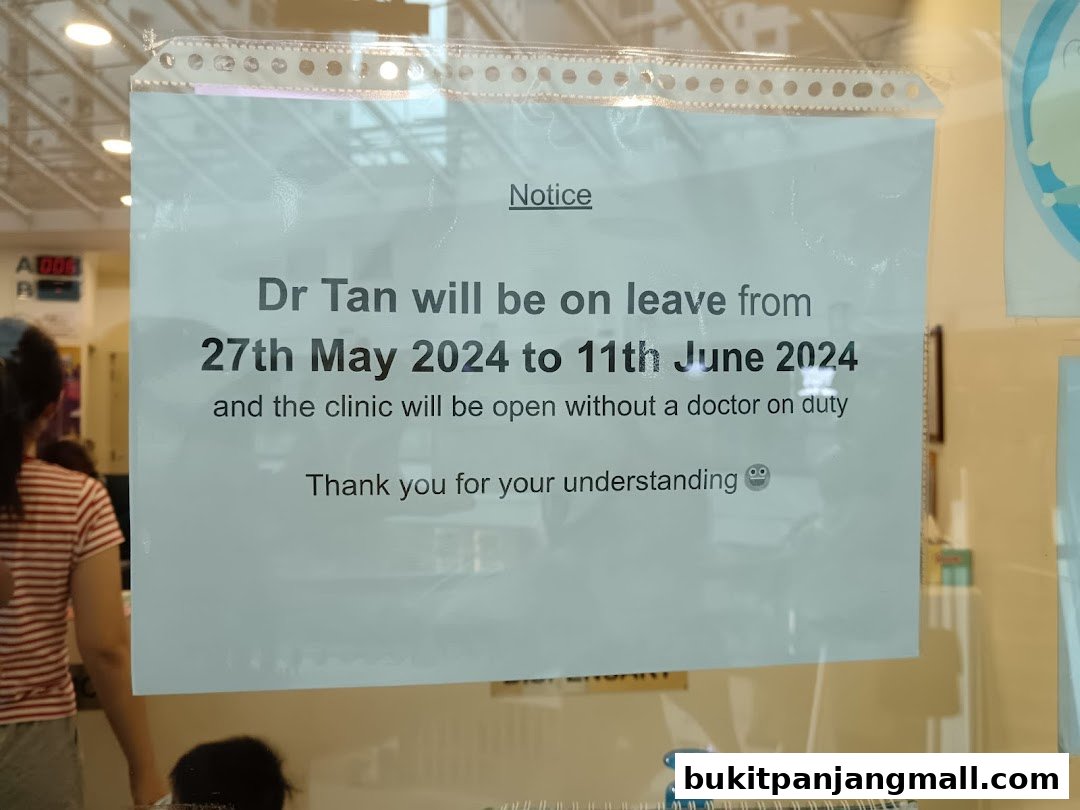 A notice on a clinic window announcing Dr. Tan's leave and clinic operating status.