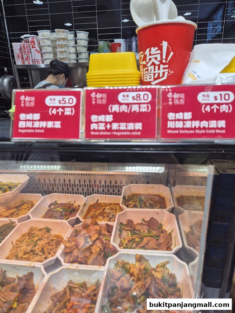 A display of various prepared dishes with price tags in a food stall.