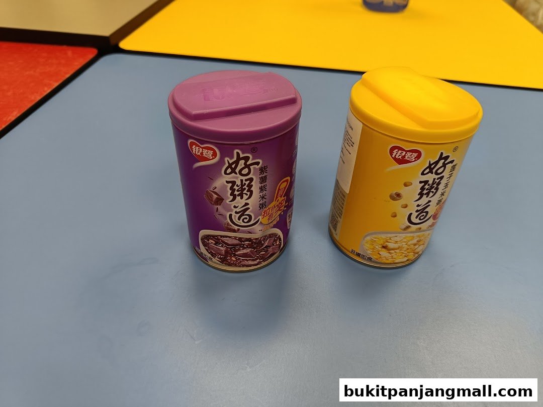 Two cans of instant porridge, one purple for purple sweet potato and black rice, and one yellow for lotus seed and corn.