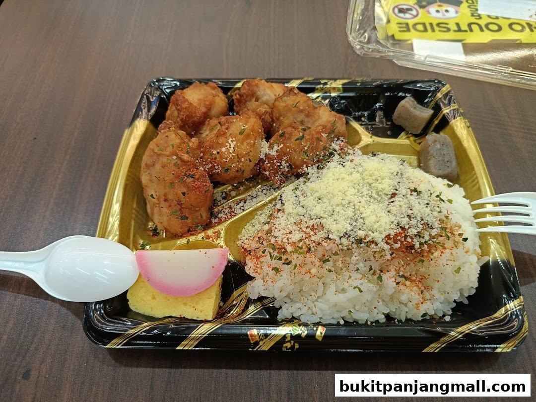 A bento box with fried chicken, rice, tamagoyaki, and pickled vegetables.