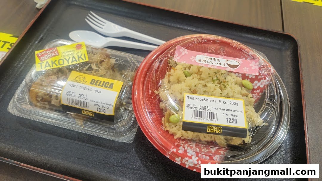 Two pre-packaged Japanese meals, Takoyaki and Mushroom & Clams Rice, with cutlery on a tray.