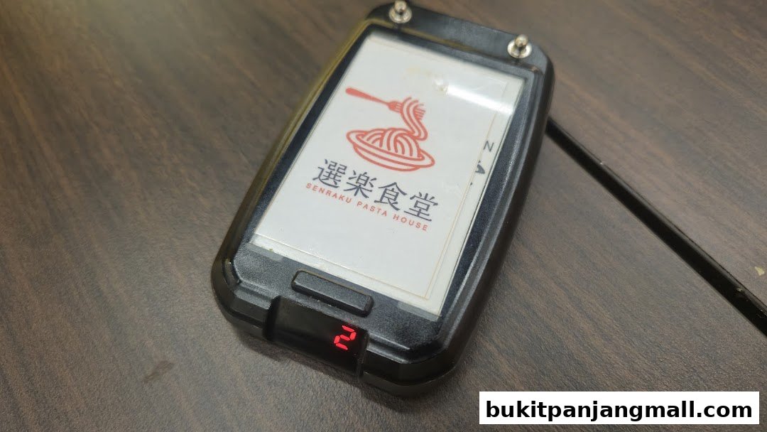 A close-up of a table pager with the Senraku Pasta House logo and a digital display showing '2'.