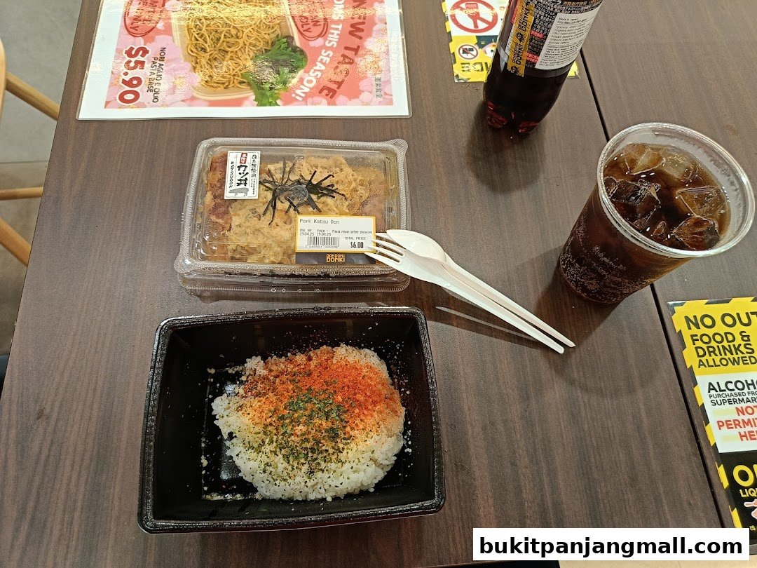 A table with a meal including rice, pork katsu, a drink, and cutlery.