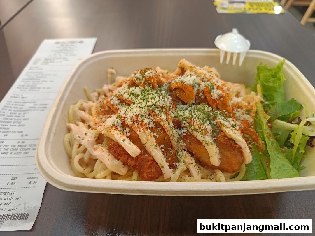 A close-up of a pasta dish with fried chicken, sauce, and a side salad, next to a receipt.