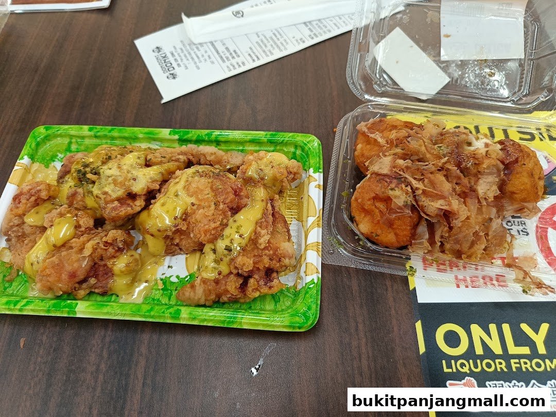 Two containers of food, one with fried chicken and sauce, the other with takoyaki.