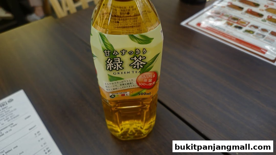 A bottle of green tea with Japanese text and nutritional information sits on a wooden table.