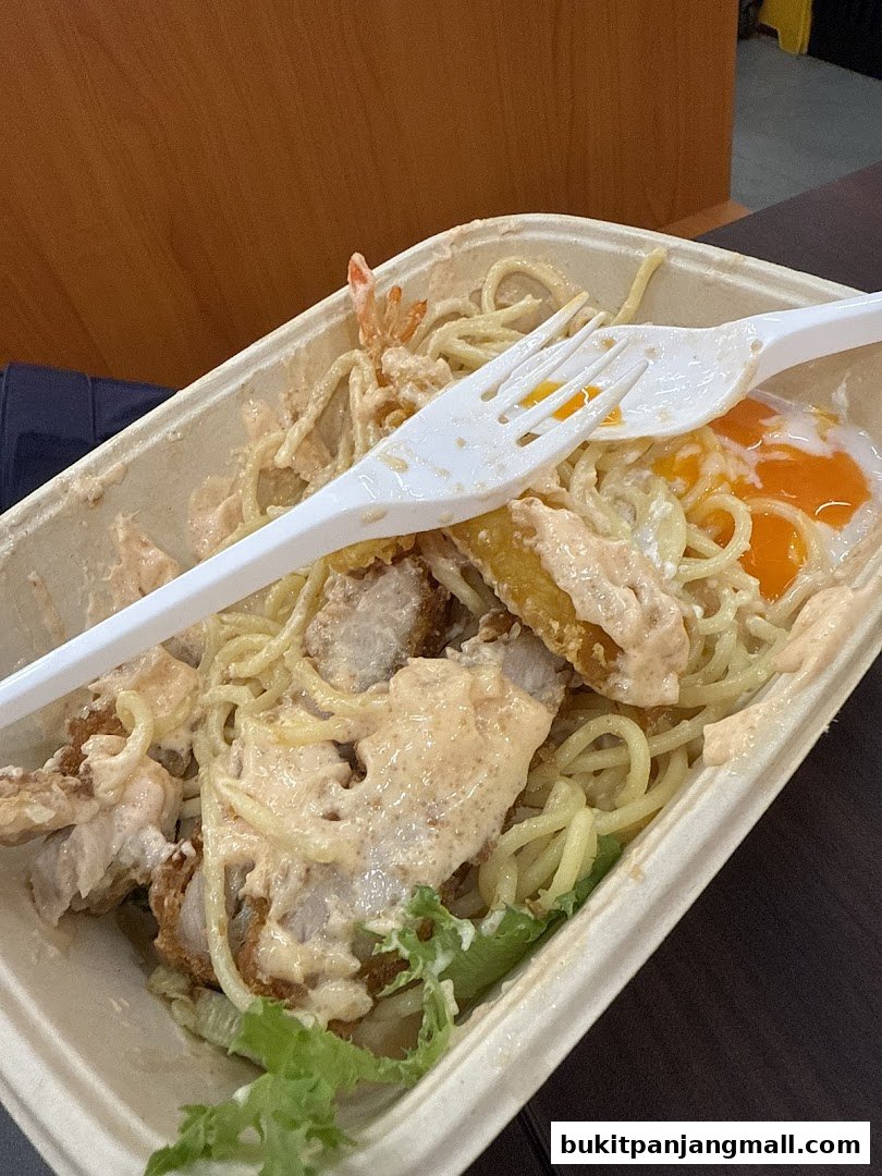 A takeout container filled with pasta, fried chicken, shrimp, and a fried egg.