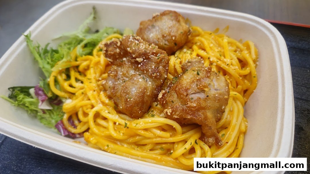 A close-up of a pasta dish with creamy orange sauce, topped with fried chicken pieces and a side salad.