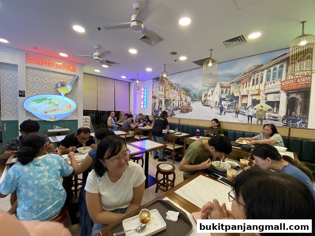 Diners enjoy meals inside a brightly lit restaurant with a scenic mural on the wall.