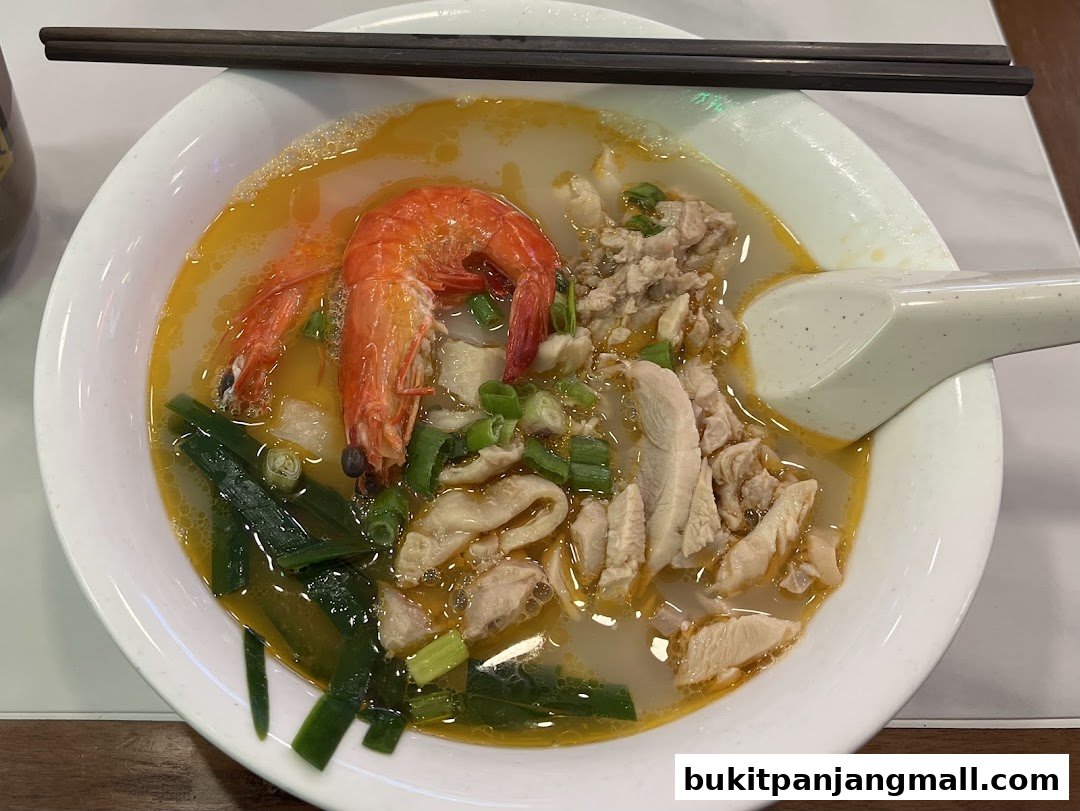 A close-up shot of a delicious bowl of Ipoh hor fun with prawn, chicken, and vegetables.